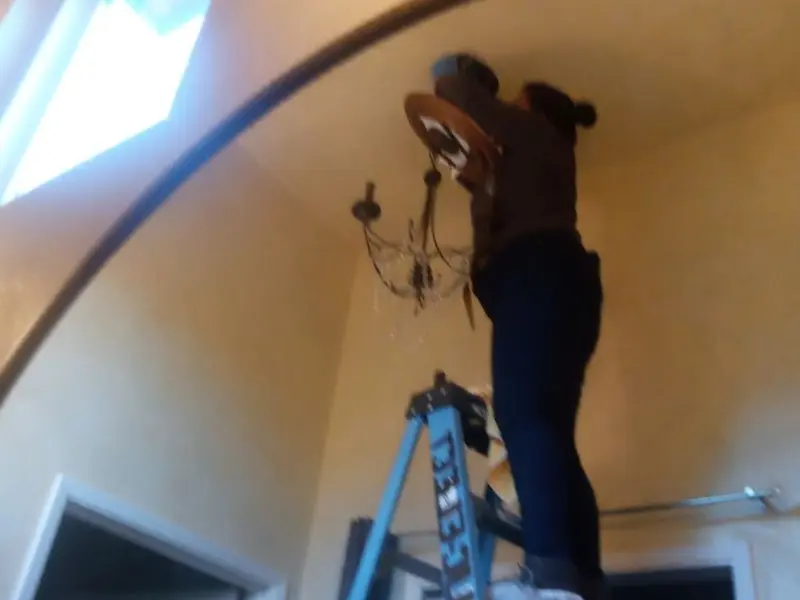 Electrician installing a chandelier in a Beebe residence
